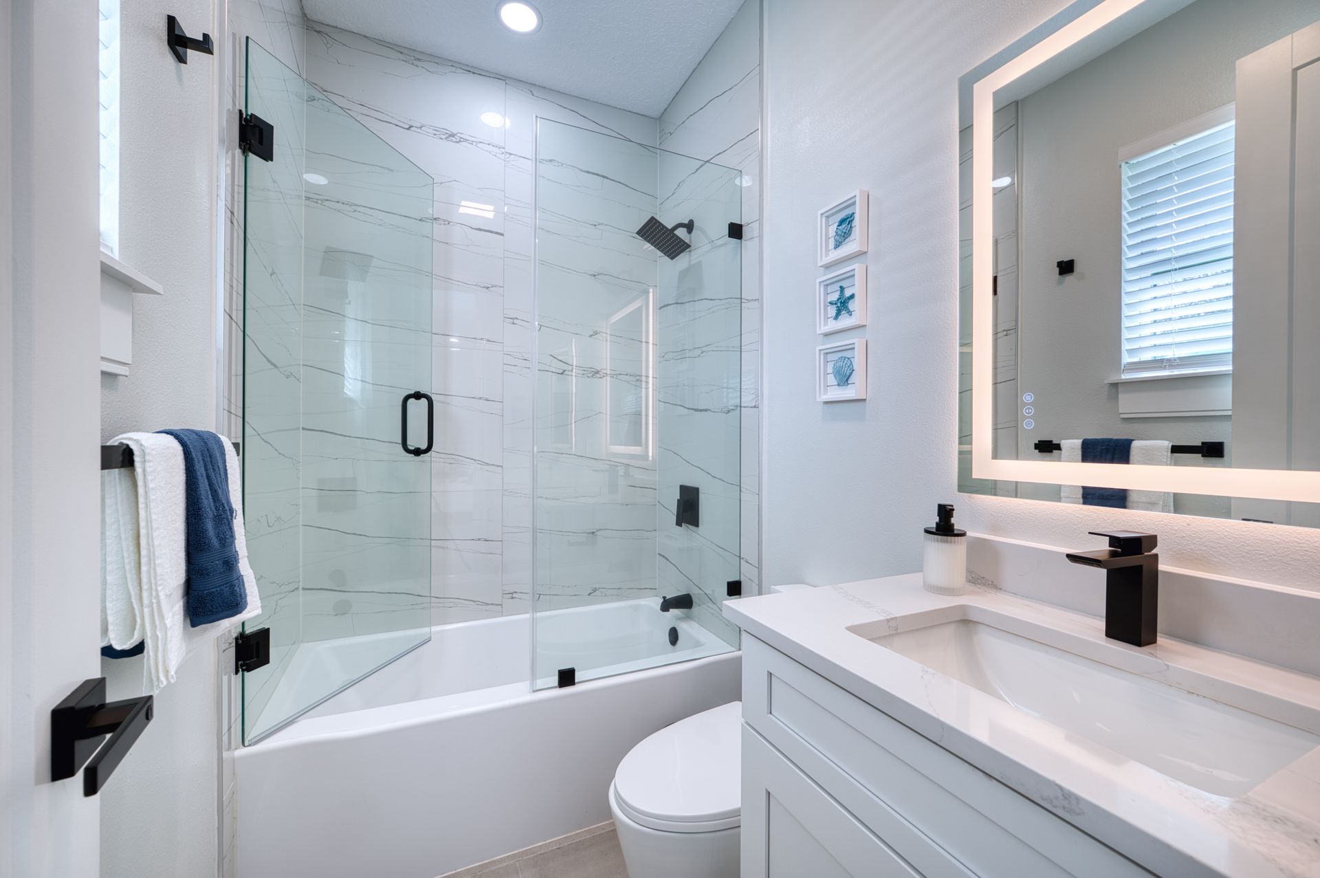 Modern white bathroom with glass shower, vanity sink, and wall mirror