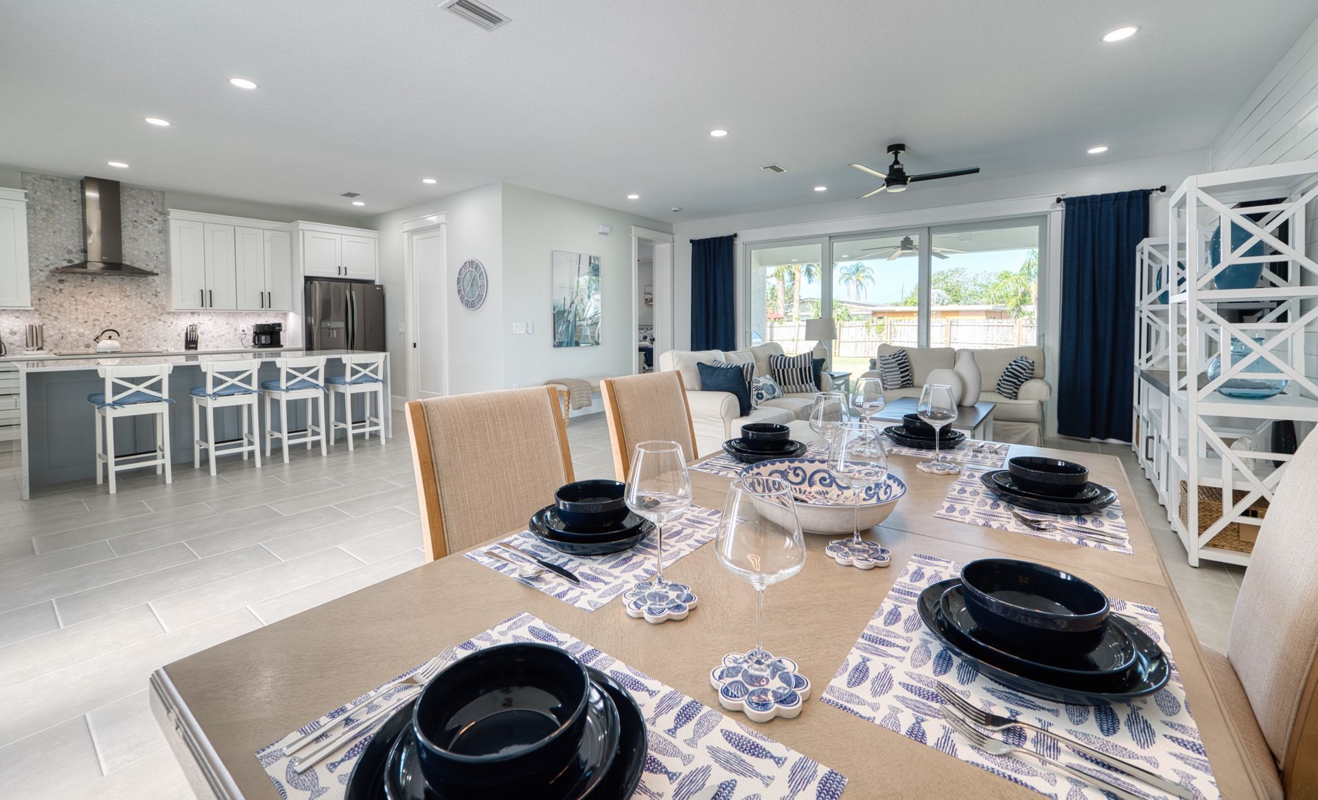 Bright open dining and kitchen area with a set table, white cabinets, and large windows