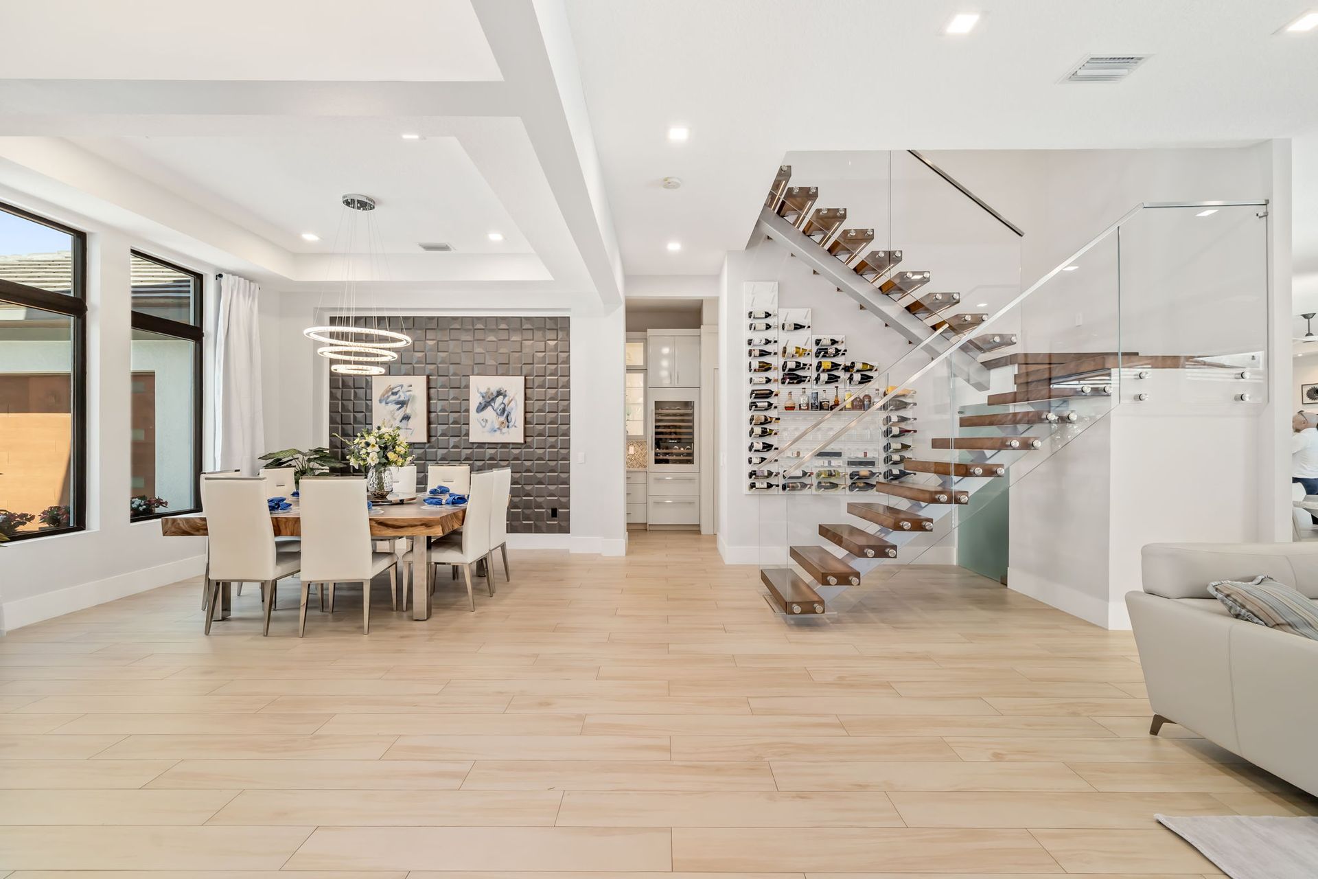 Bright modern dining and living area with floating staircase and light wood floors