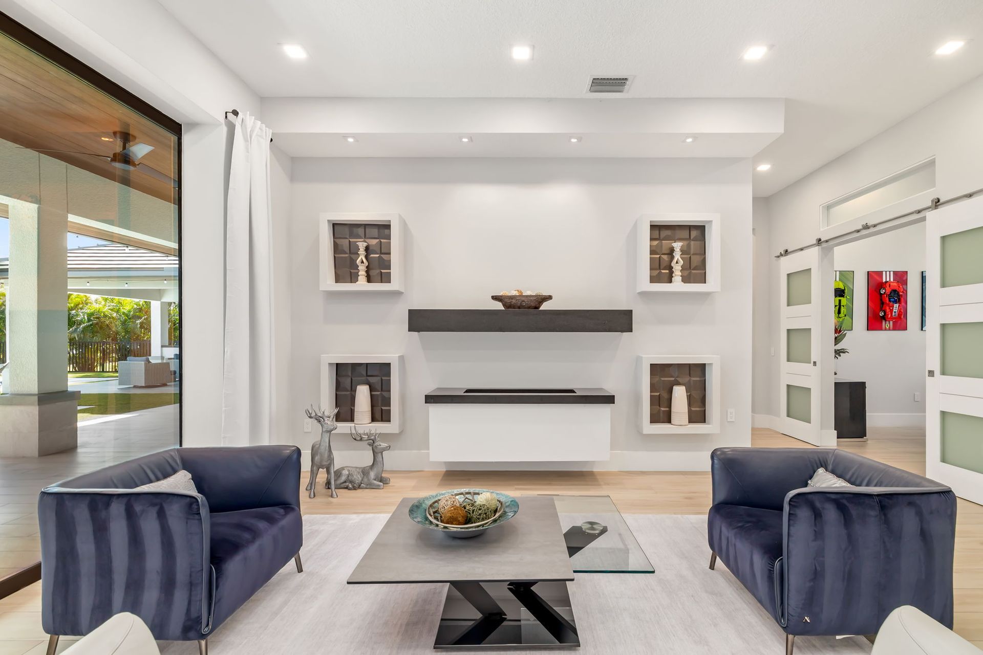 Bright modern living room with white fireplace, navy sofas, and a glass coffee table