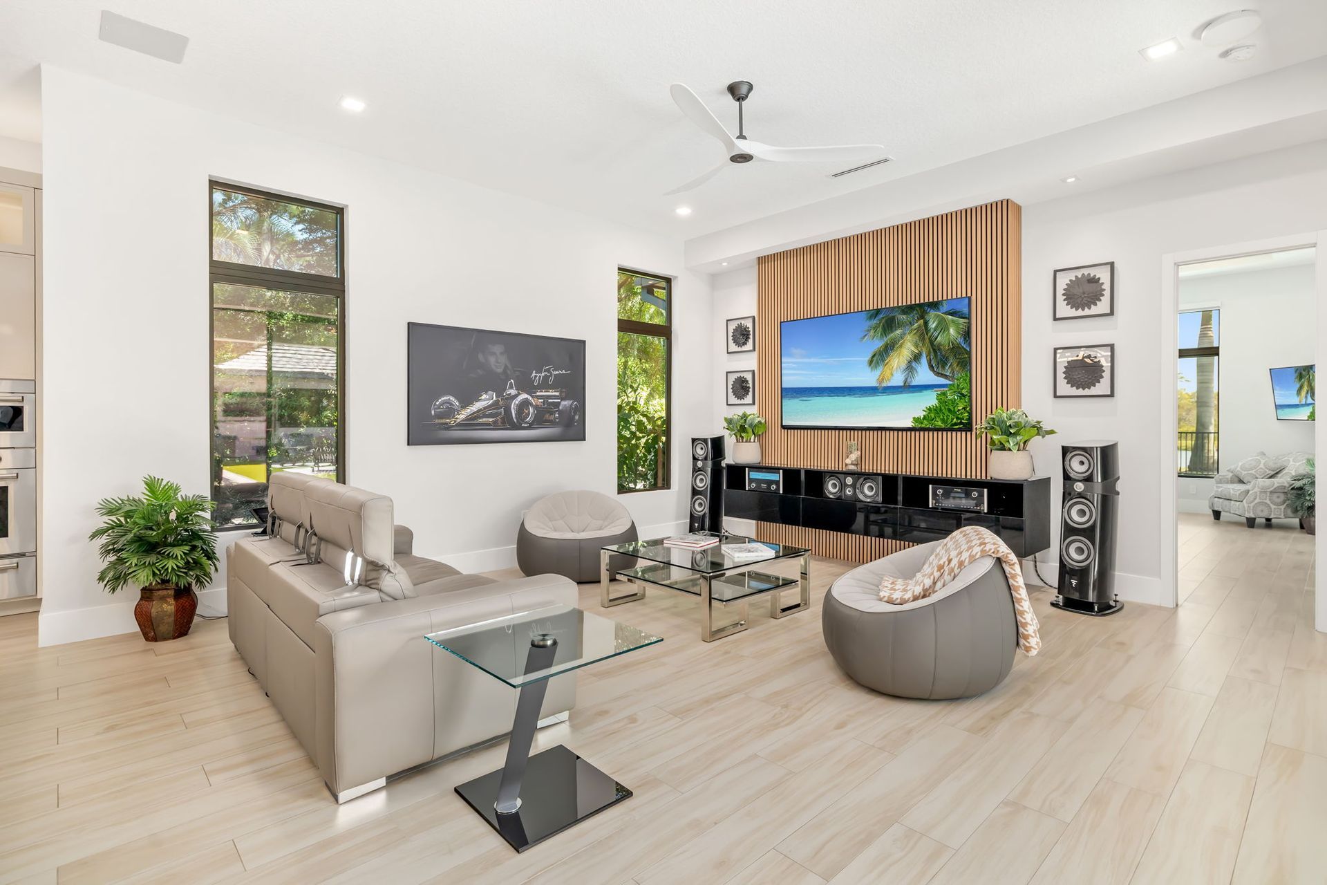 Bright modern living room with a sectional sofa, TV, large windows, and light wood floors