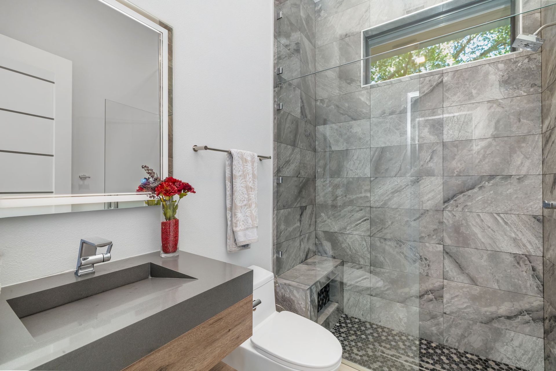 Modern bathroom with gray stone shower, floating vanity, and wall mirror