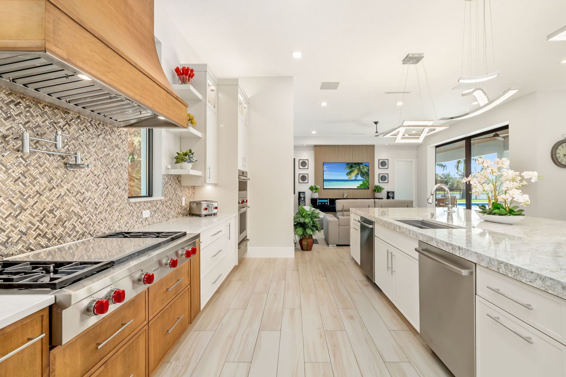 Bright modern kitchen with white cabinets, granite counters, stainless appliances, and a large island near a window.