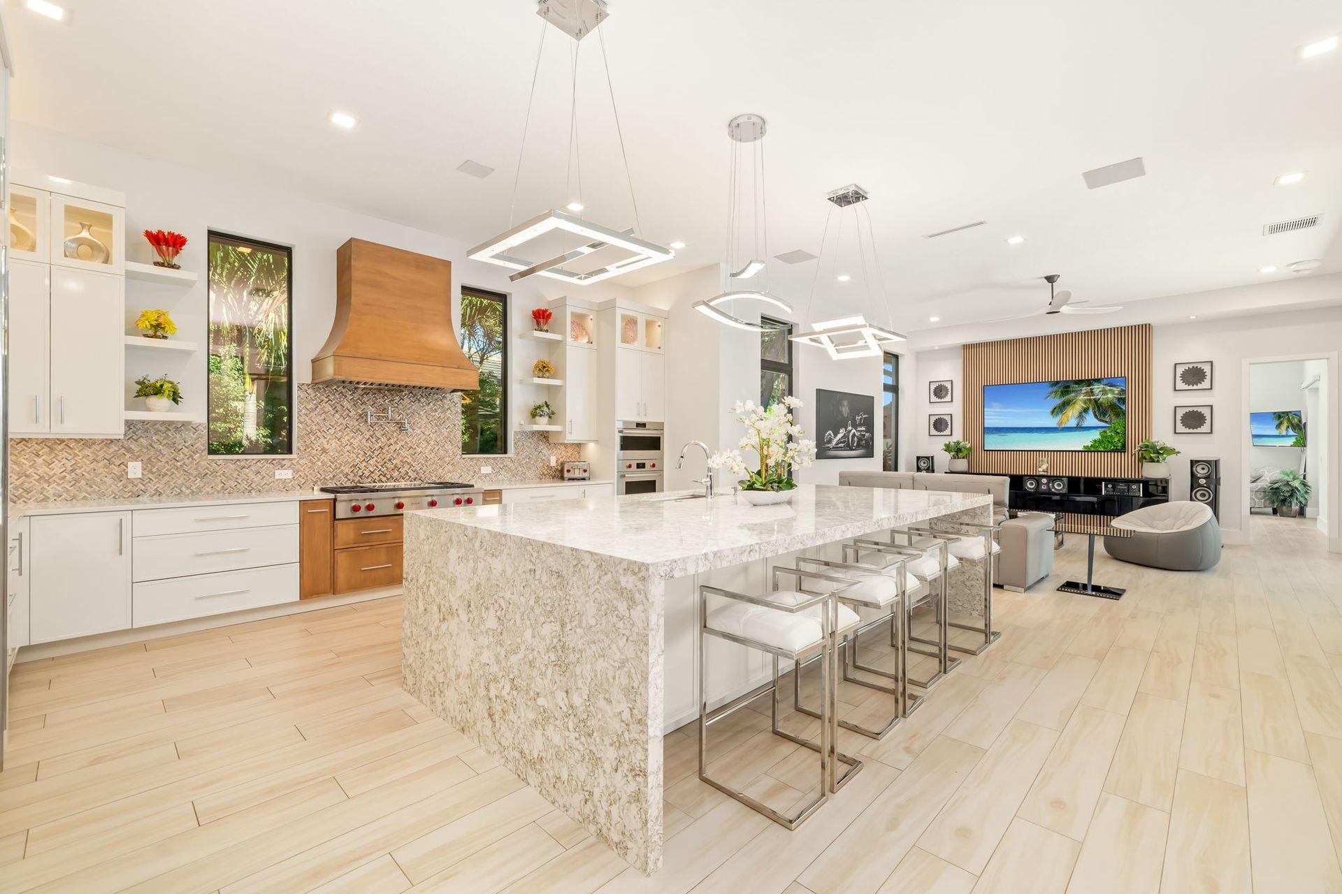 Modern open kitchen with marble island, white cabinets, wood accents, and dining area in the background