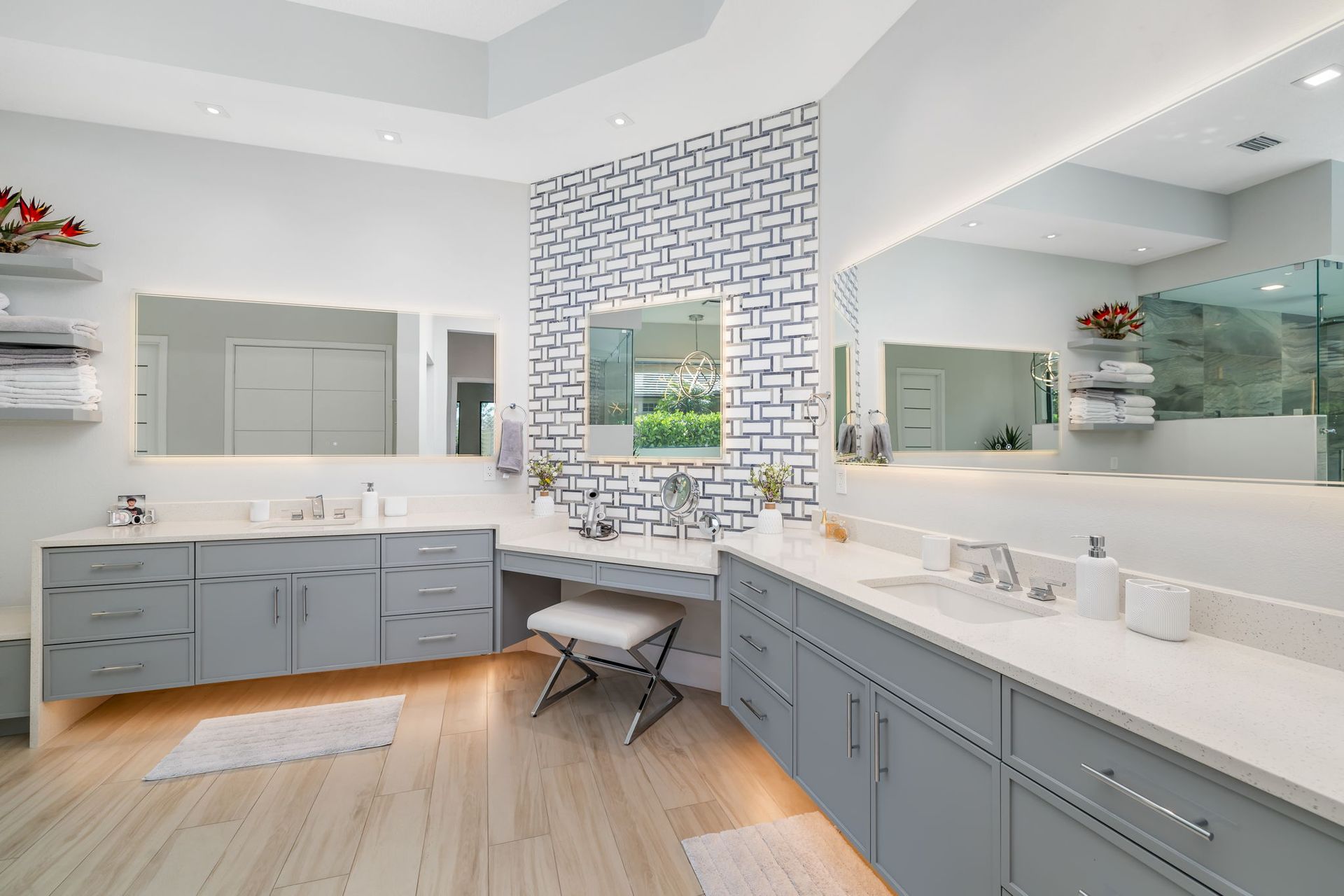 Modern bathroom with double vanity, large mirror, white countertops, gray cabinets, and patterned accent wall