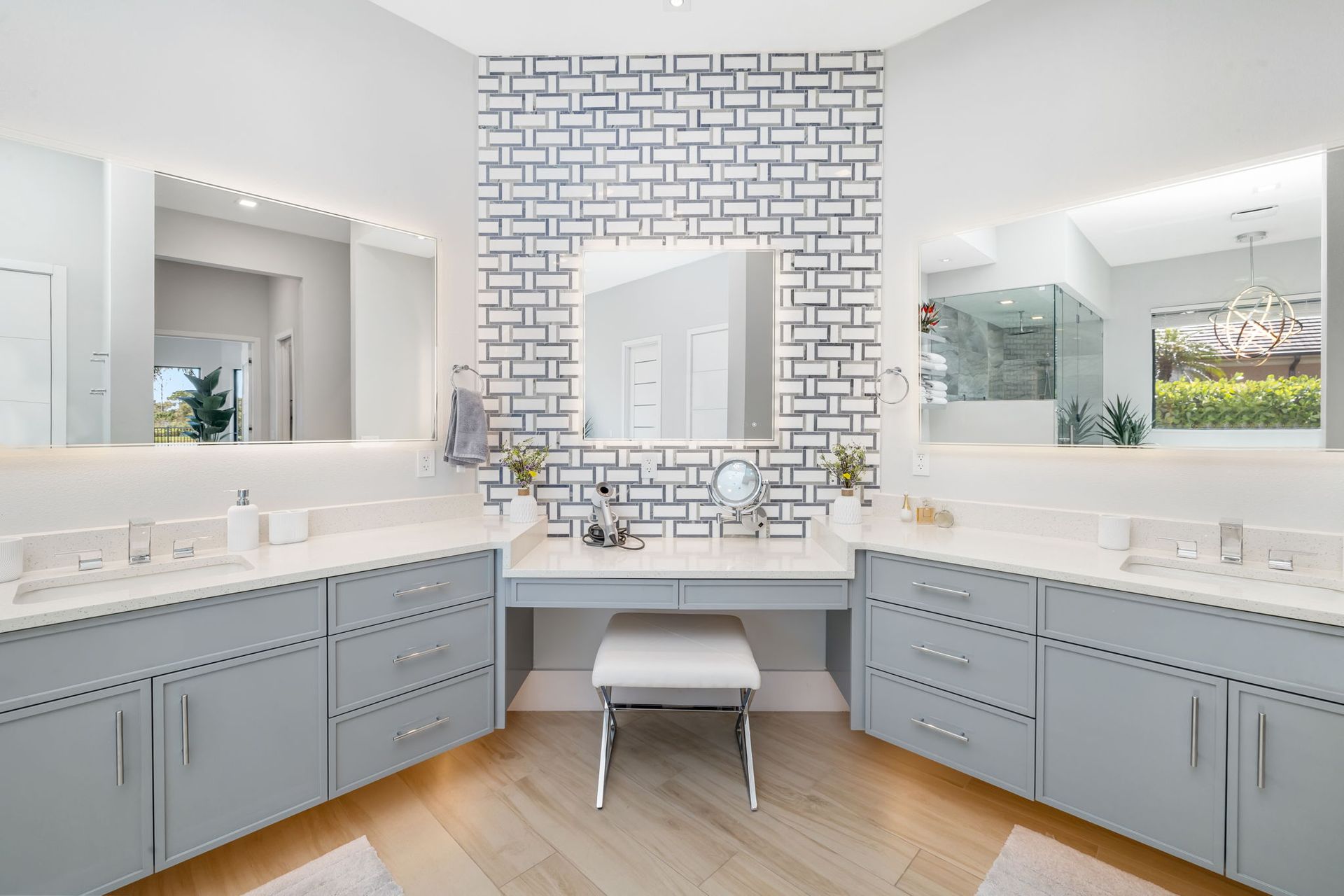 Bright modern double vanity bathroom with gray cabinets, large mirrors, and a patterned accent wall