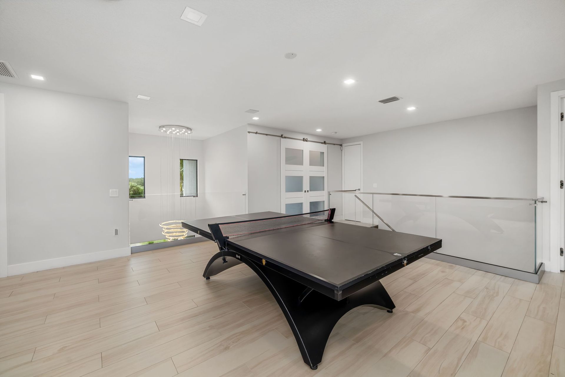 Modern white room with a black air hockey table and light wood floors