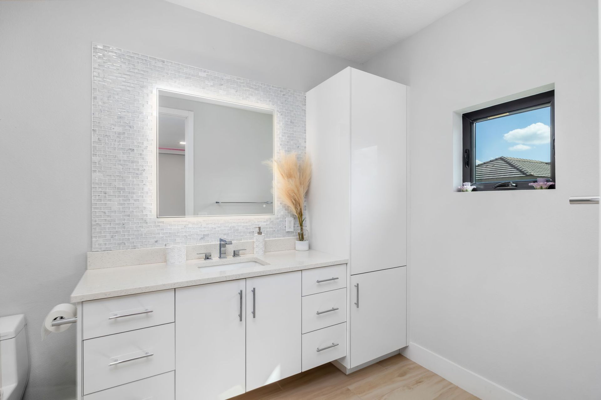 Modern white bathroom vanity with mosaic mirror, tall cabinet, and small window