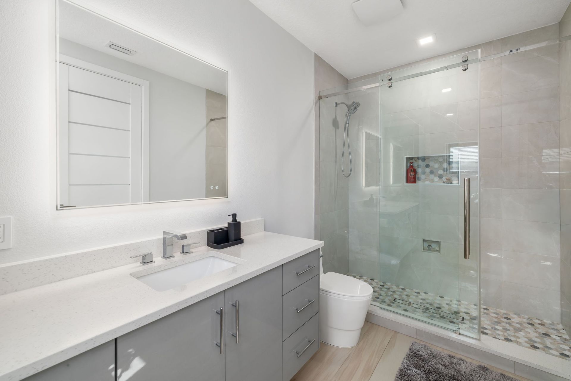 Modern bathroom with double vanity, large mirror, and glass walk-in shower