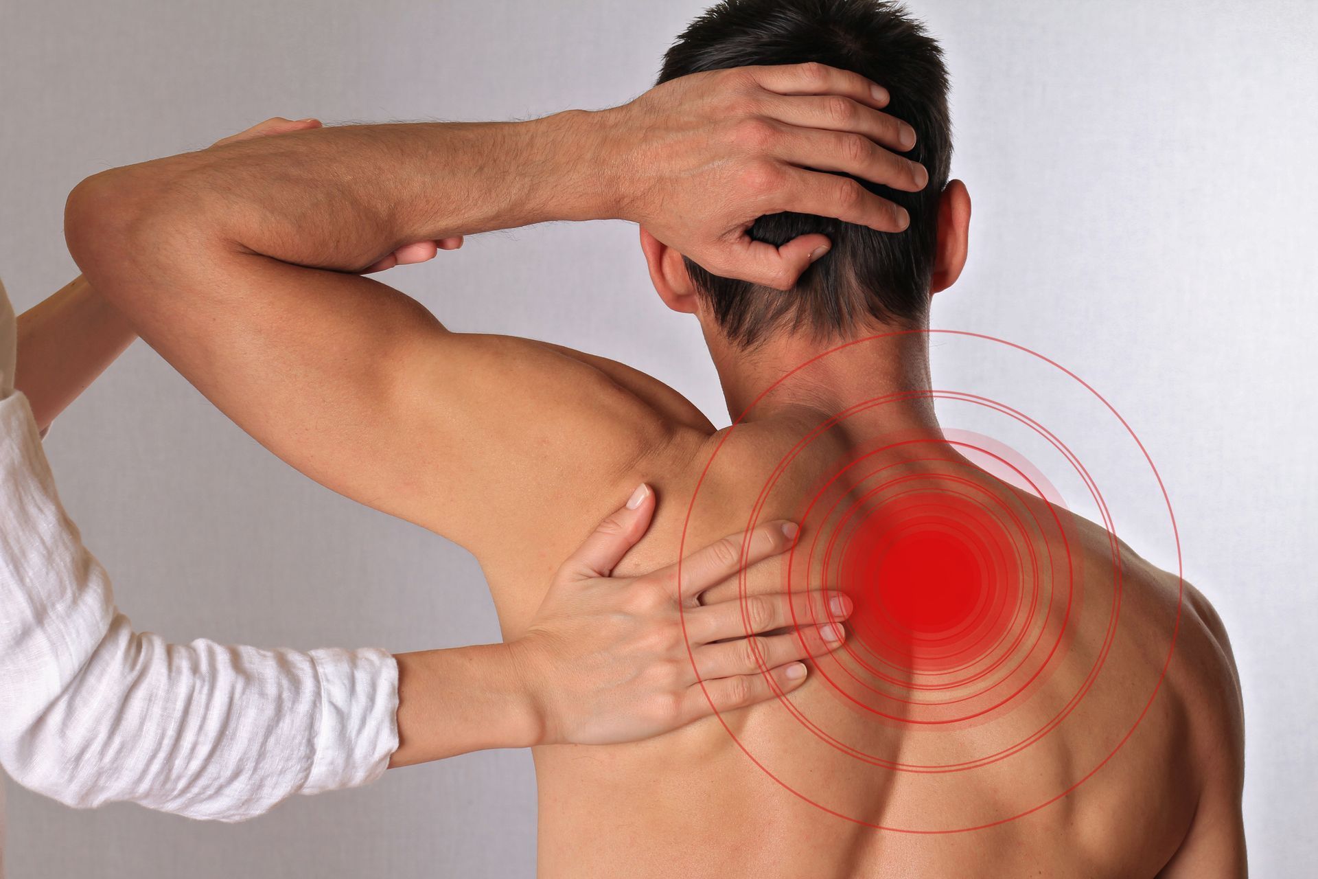 Person receiving shoulder massage, highlighted with red pain area.