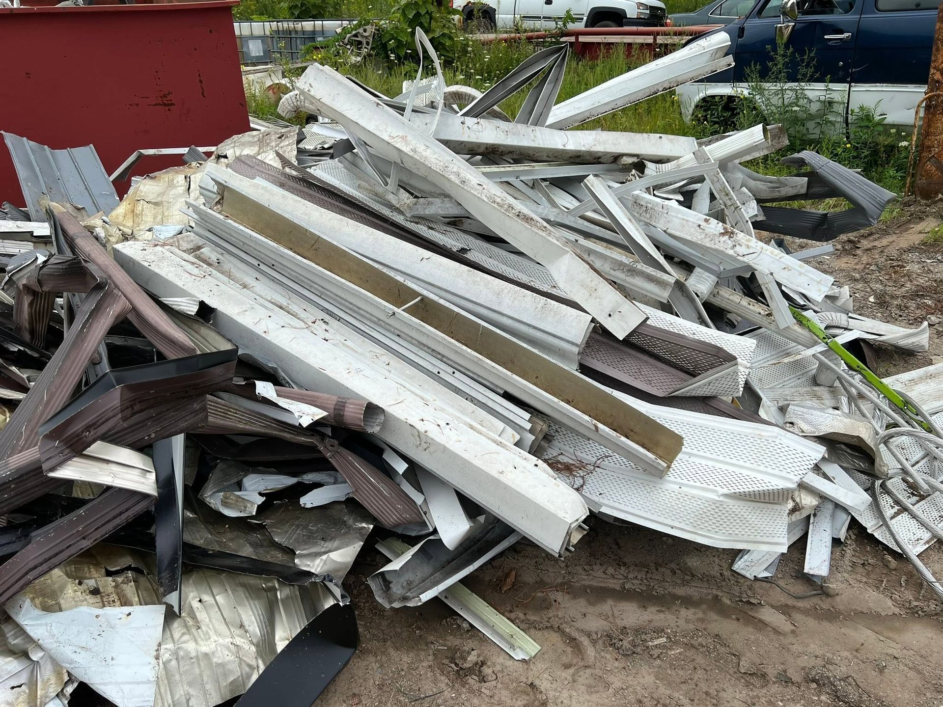 Pile of broken white and dark construction debris stacked outdoors near a red building