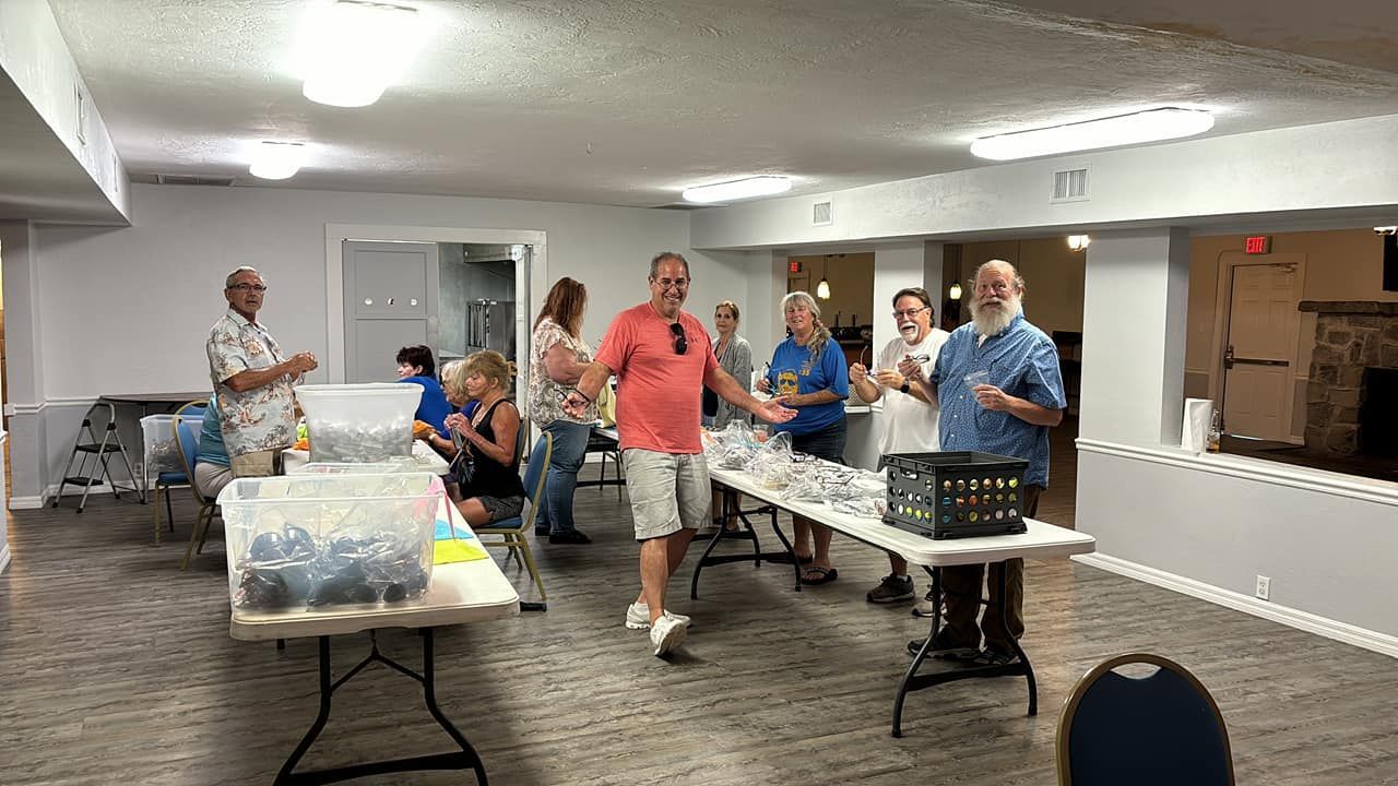A group of people are standing around tables in a room.