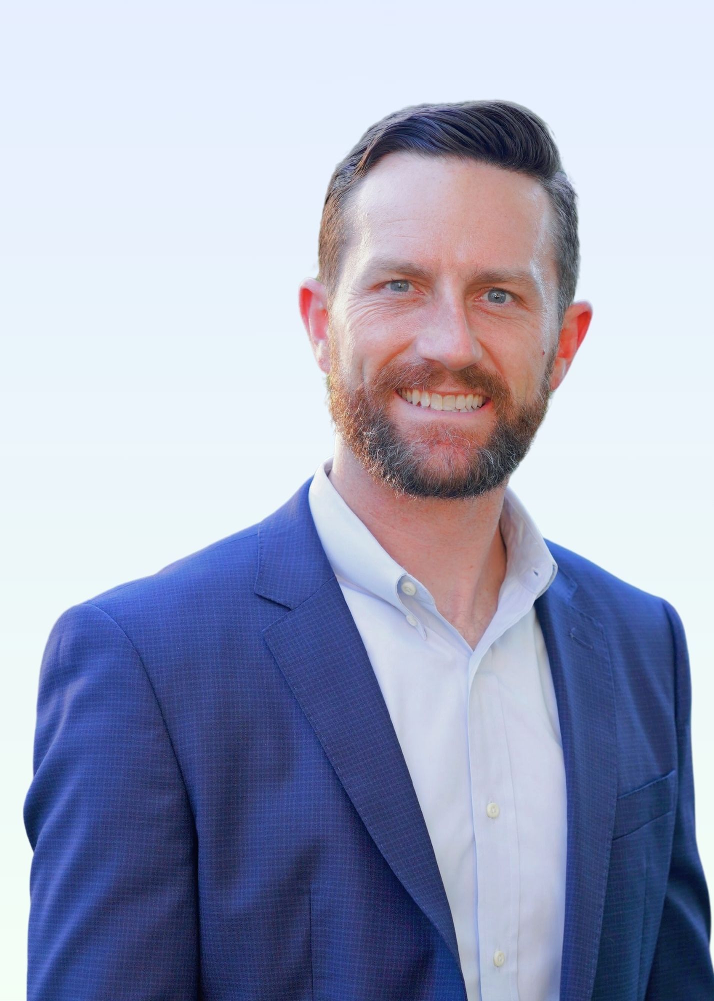 A man in a suit and white shirt is smiling for the camera.