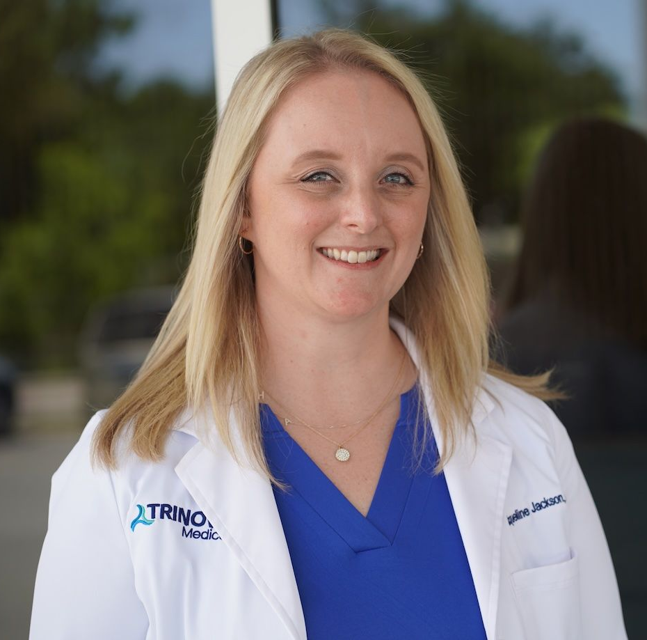 Smiling doctor in blue scrubs and white lab coat standing outdoors