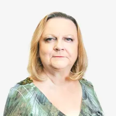 A woman in a green shirt is standing in front of a white background.