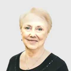 A woman wearing a black shirt and a necklace is smiling for the camera.