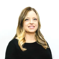 The woman is wearing a black shirt and smiling for the camera.