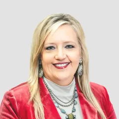 A woman wearing a red jacket and a necklace is smiling for the camera.