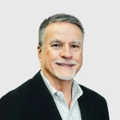A man with a beard is wearing a suit and smiling.