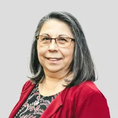 A woman wearing glasses and a red jacket is smiling for the camera.