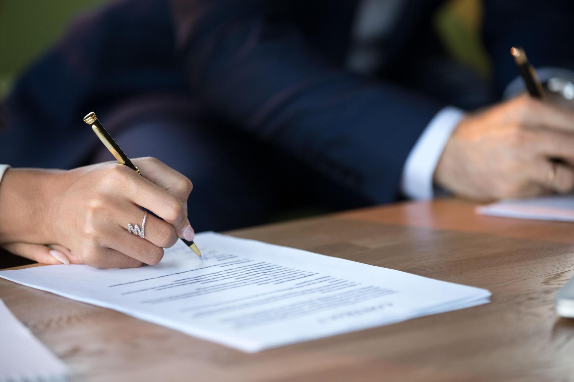 Hands signing legal documents at a table.