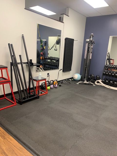 Fitness studio with exercise equipment, including weights, a mirror, and resistance machines.