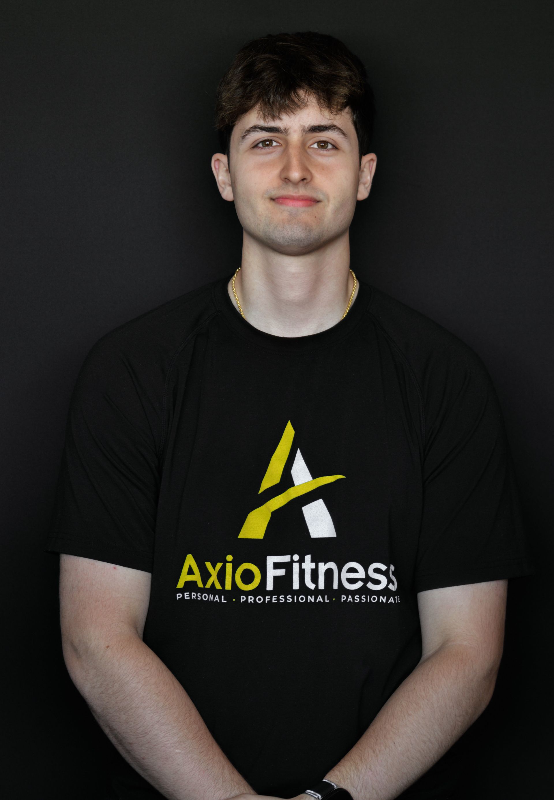 Person standing against a dark background wearing a black AxioFitness T-shirt, facing forward.