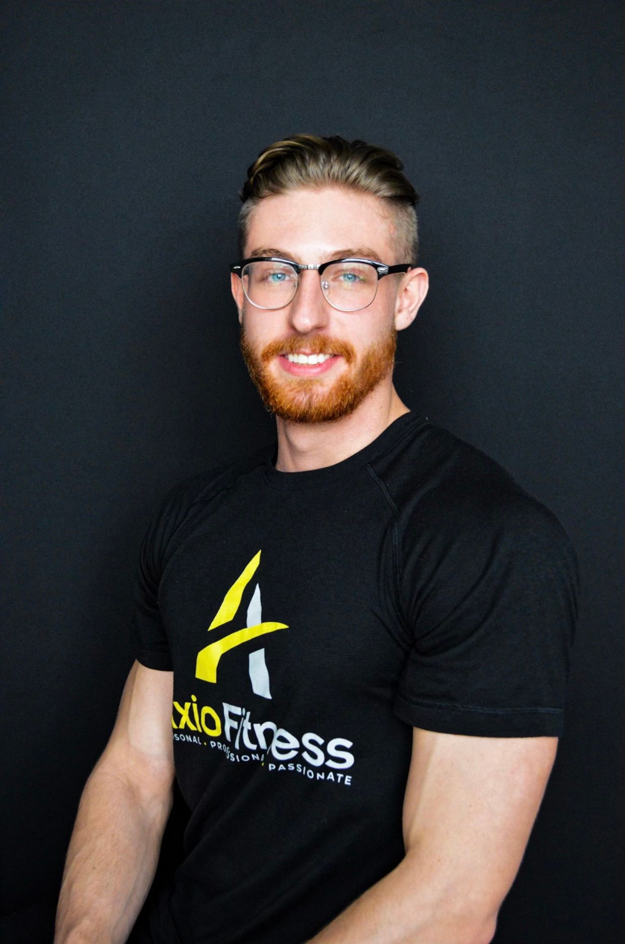 Man with glasses and a red beard, wearing a black t-shirt with a logo, smiling at the camera.