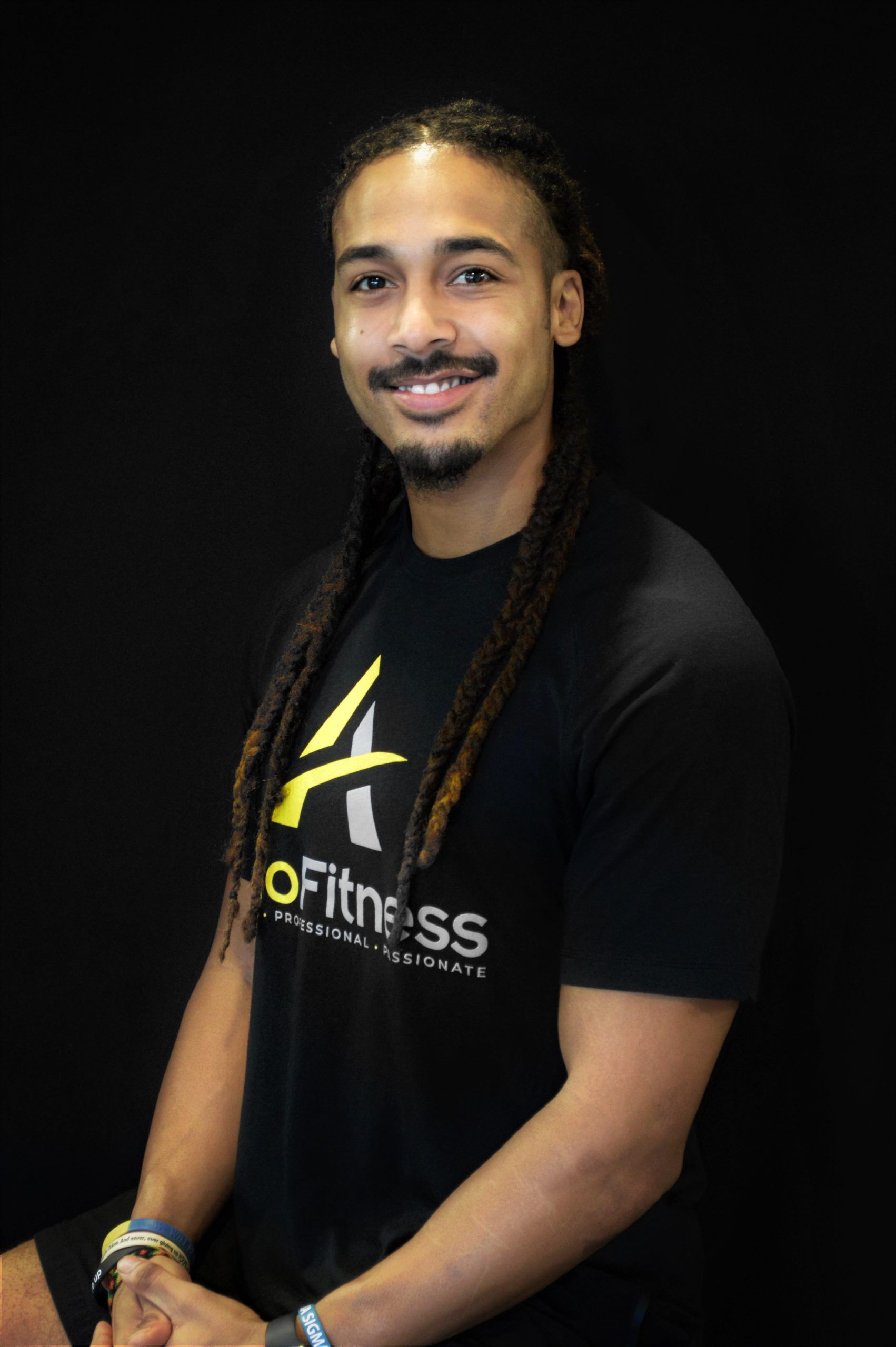 A smiling man with dreadlocks wearing a black 