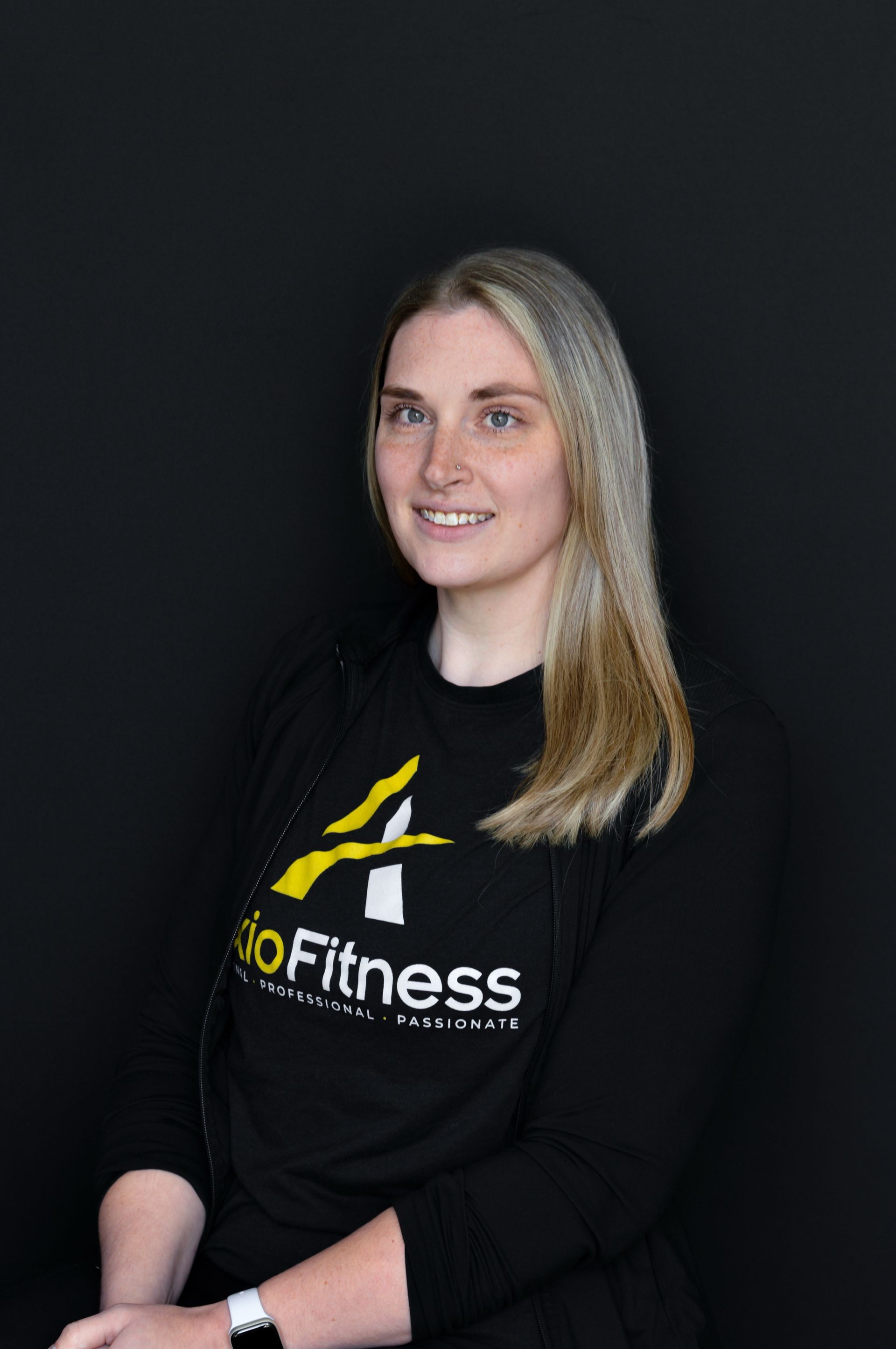 A smiling Black man wearing a black AxiFitness sweatshirt poses against a dark background.