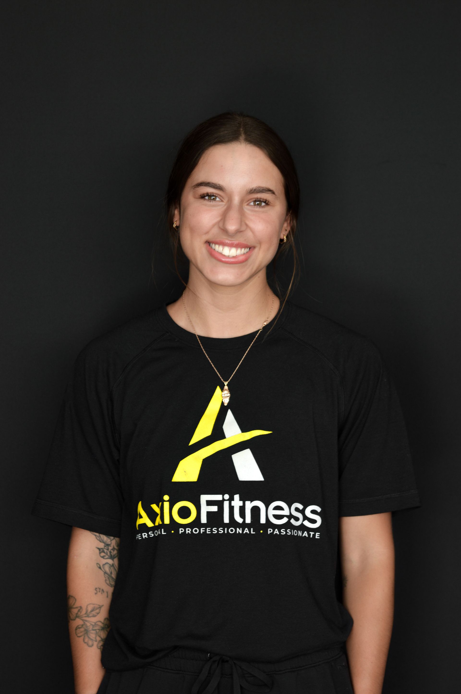 Man with a large beard, wearing a black AxioFitness t-shirt, smiling, against a gray background.