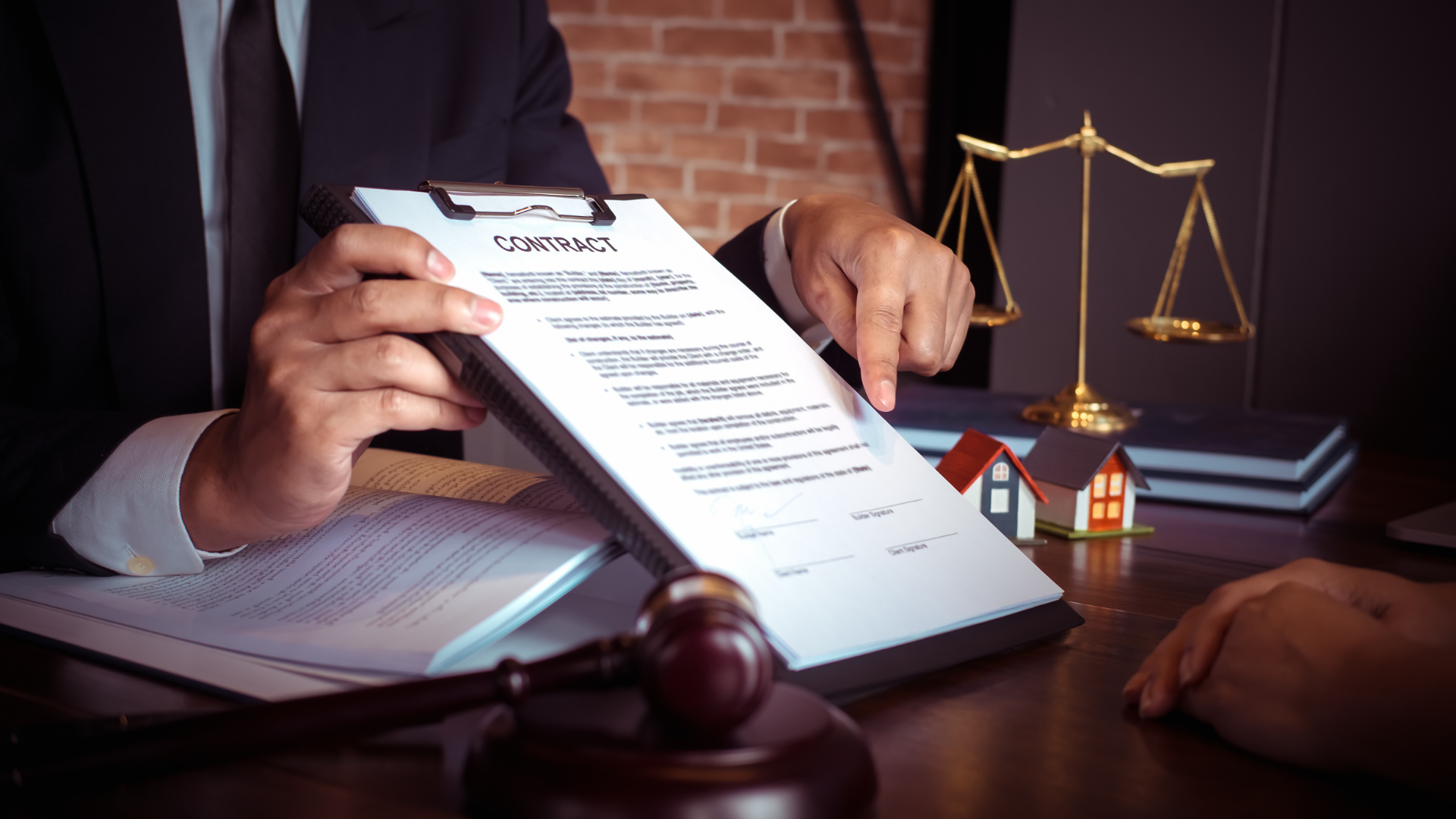 Hands reviewing a legal document beside a judge’s gavel and scales of justice on a desk
