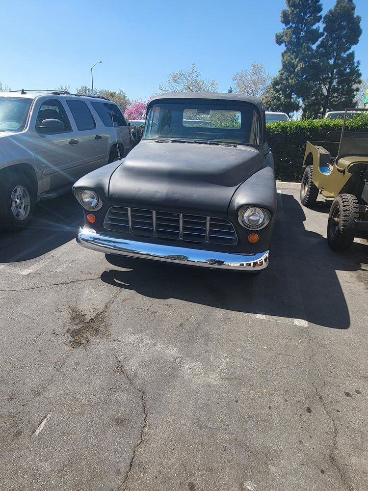 A black truck is parked in a parking lot next to a jeep.
