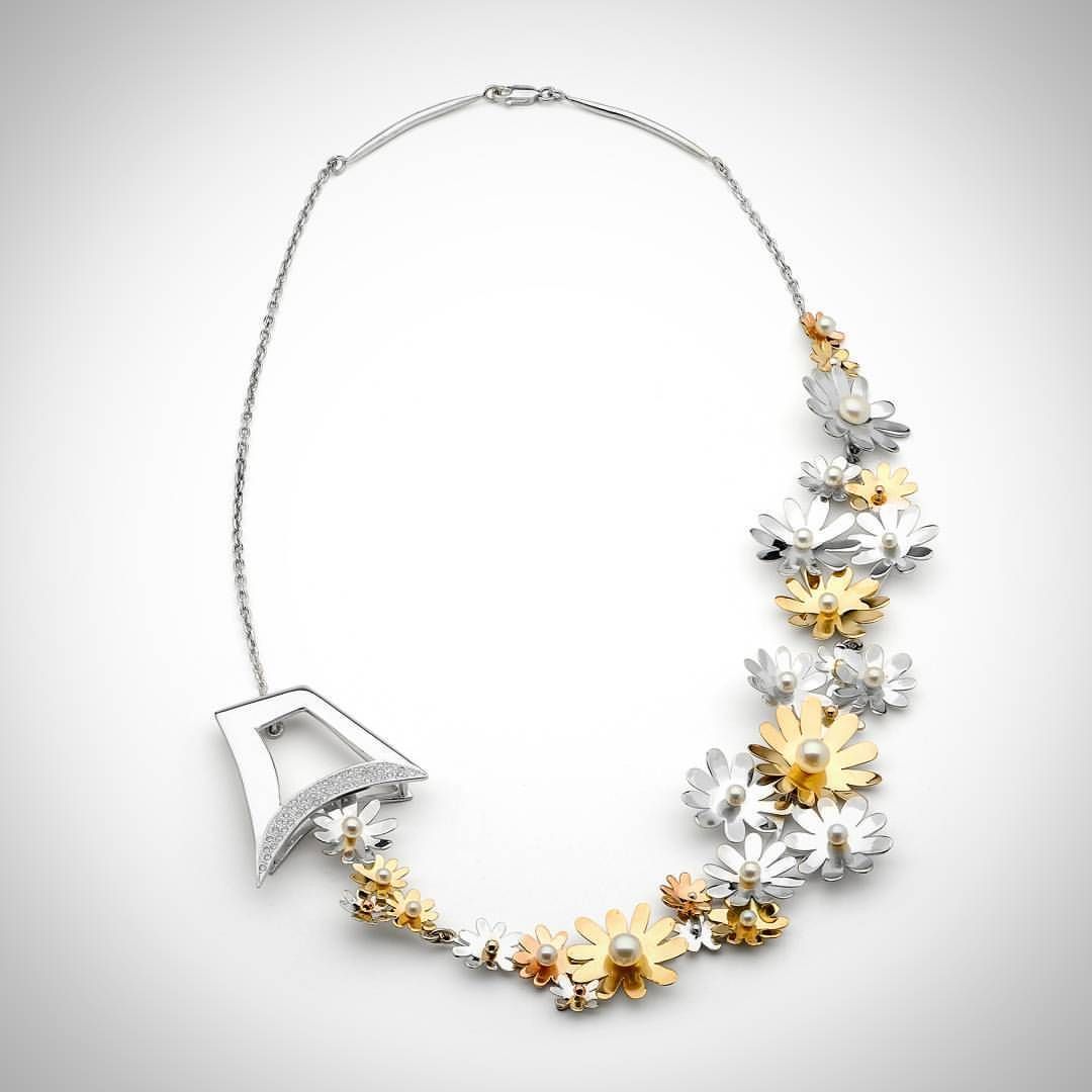 A silver and gold necklace with flowers on it