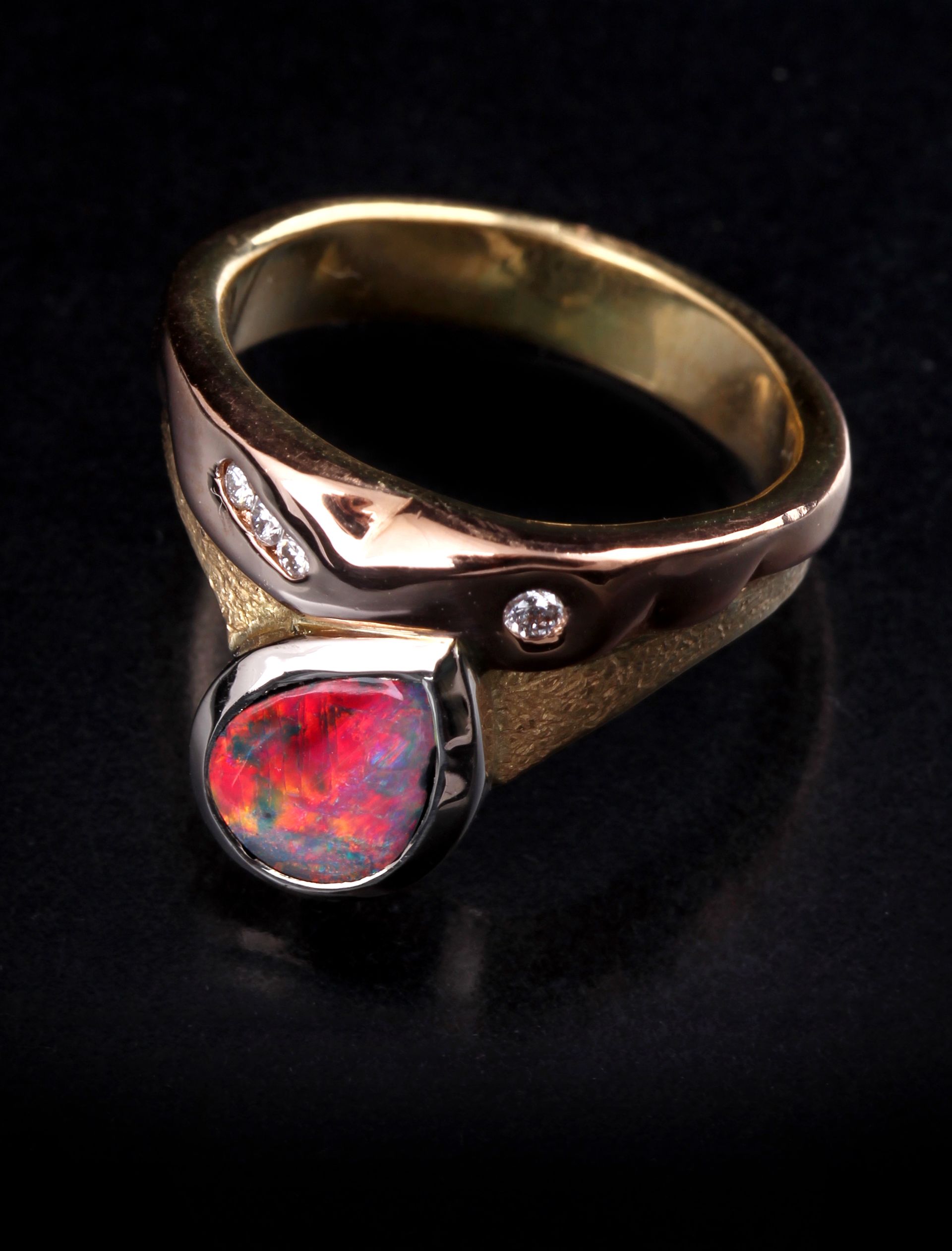 A gold ring with a red stone and diamonds