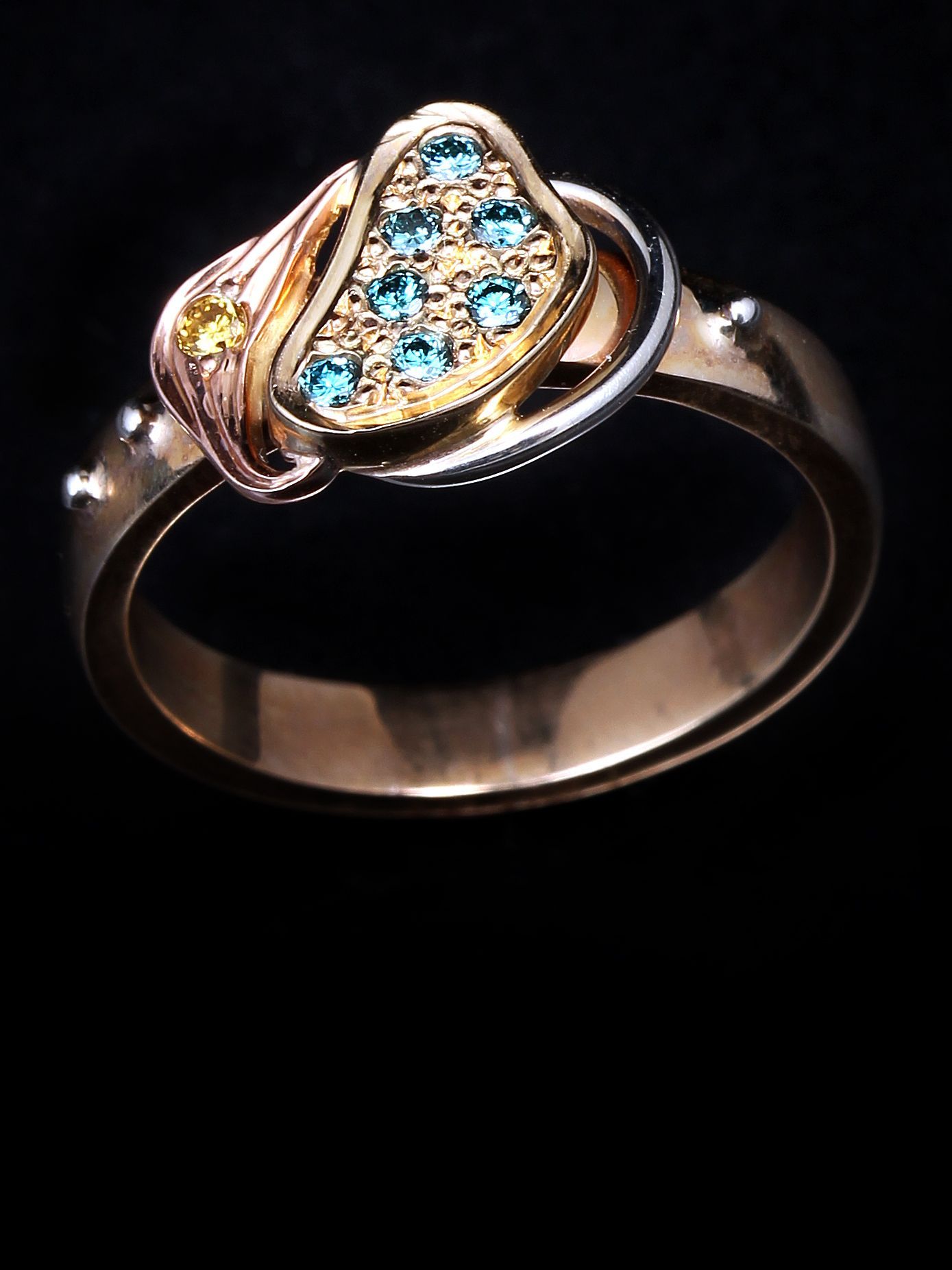 A gold ring with blue and yellow stones on a black background