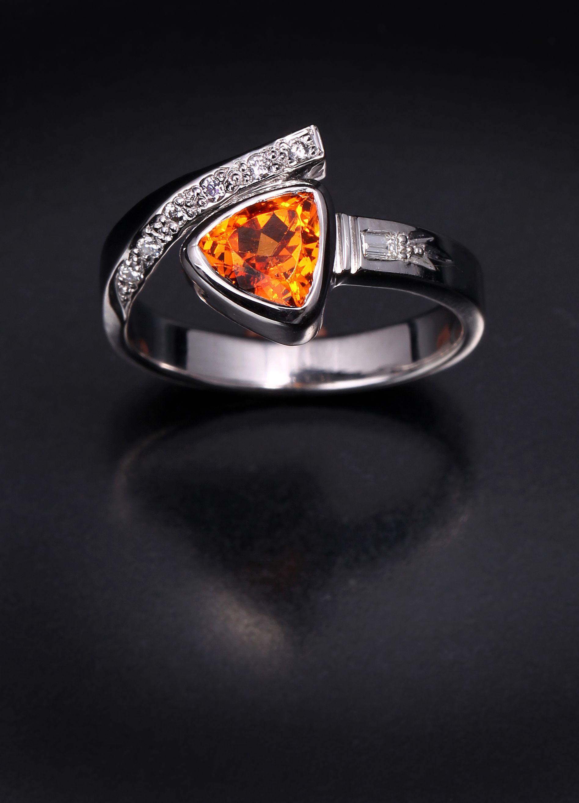 A ring with an orange stone and diamonds on a black background