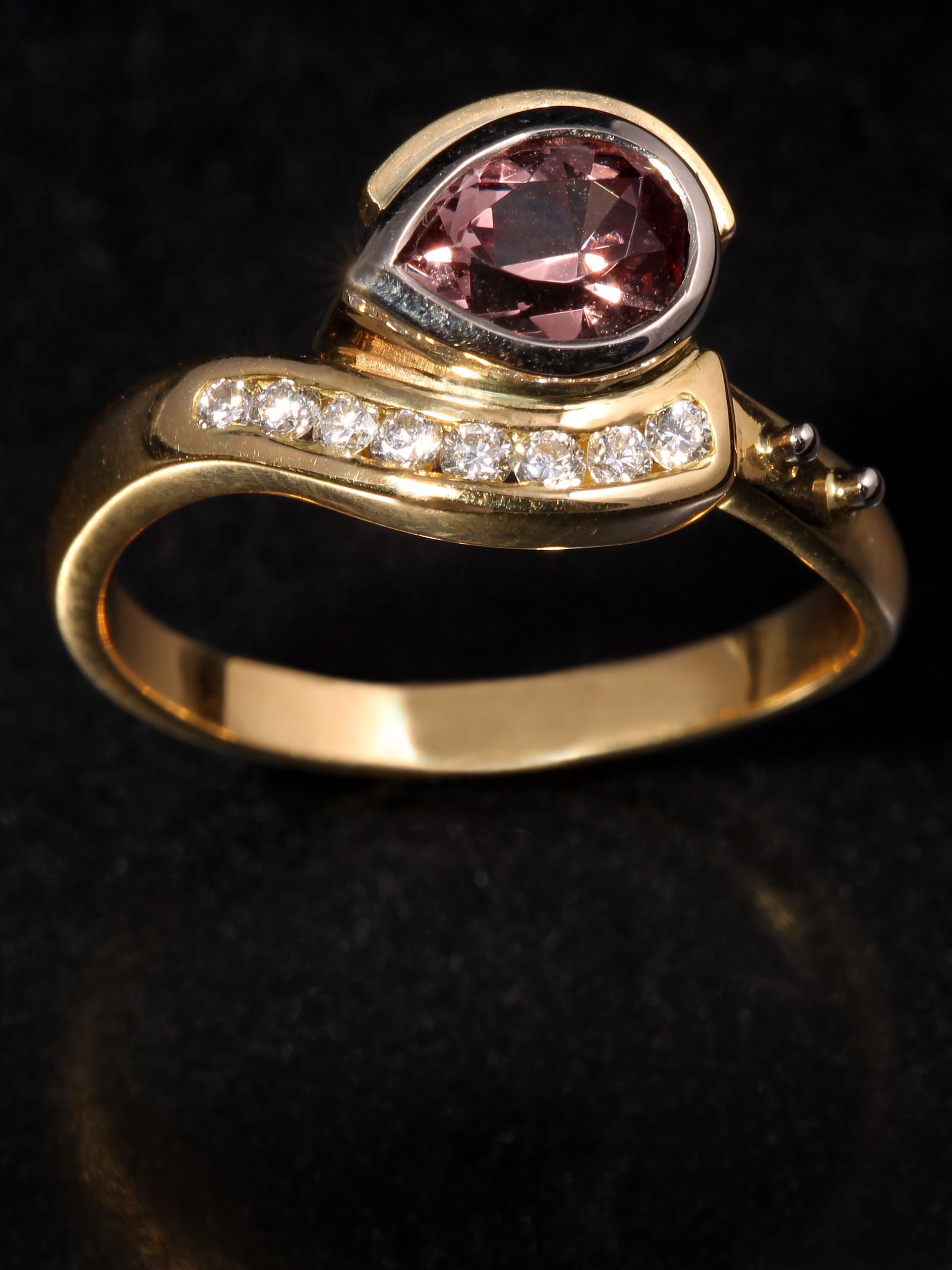 A gold ring with a pink stone and diamonds