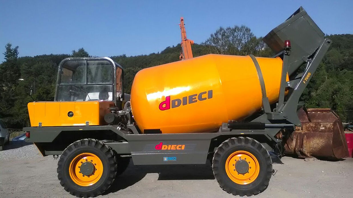 Autobetoniera autocaricante arancione e grigia in un cantiere edile.