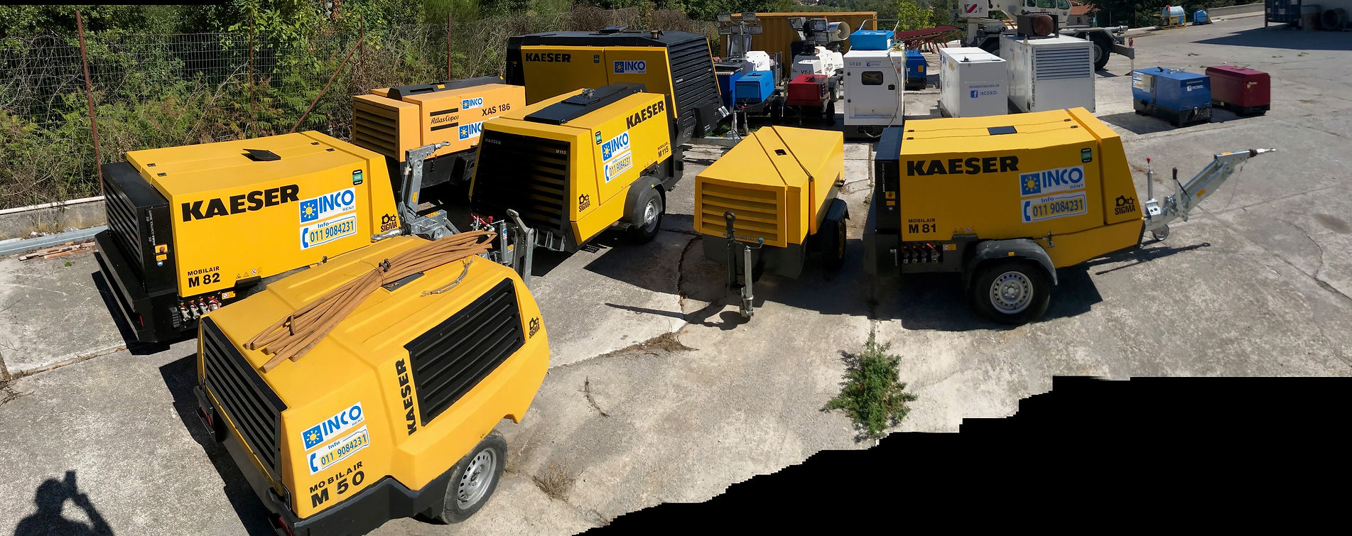 Diversi compressori d'aria Kaeser gialli parcheggiati su una superficie di cemento.