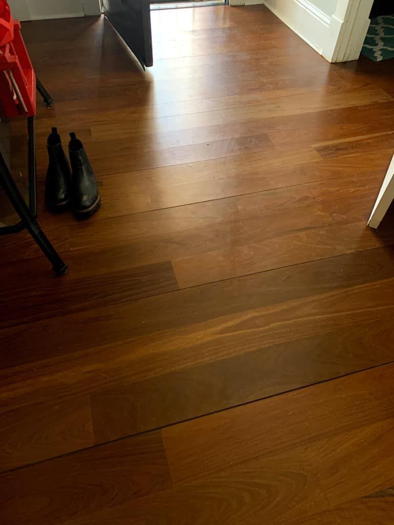 A pair of black boots are sitting on a wooden floor.