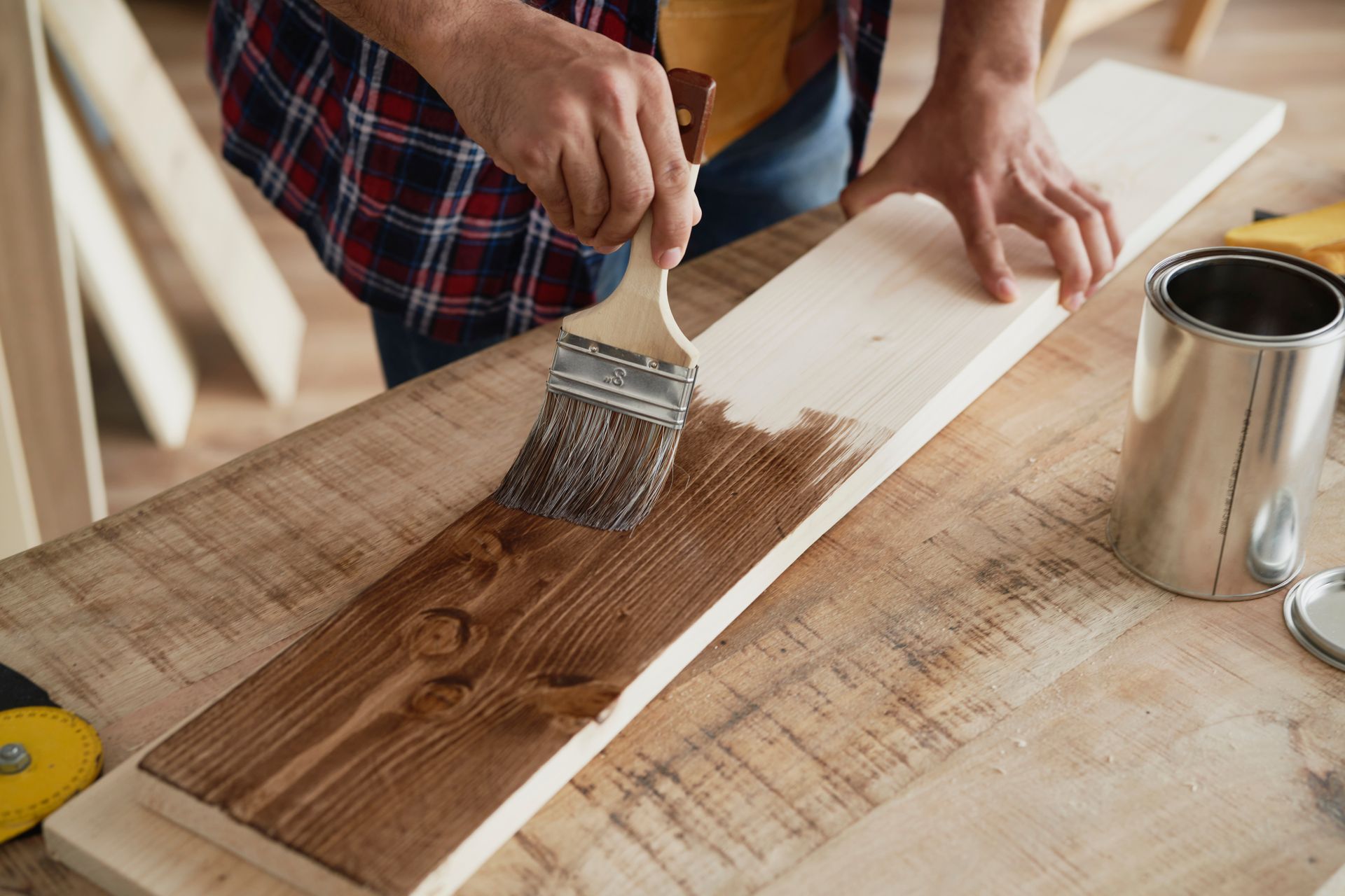detail of man painting raw board with a stain