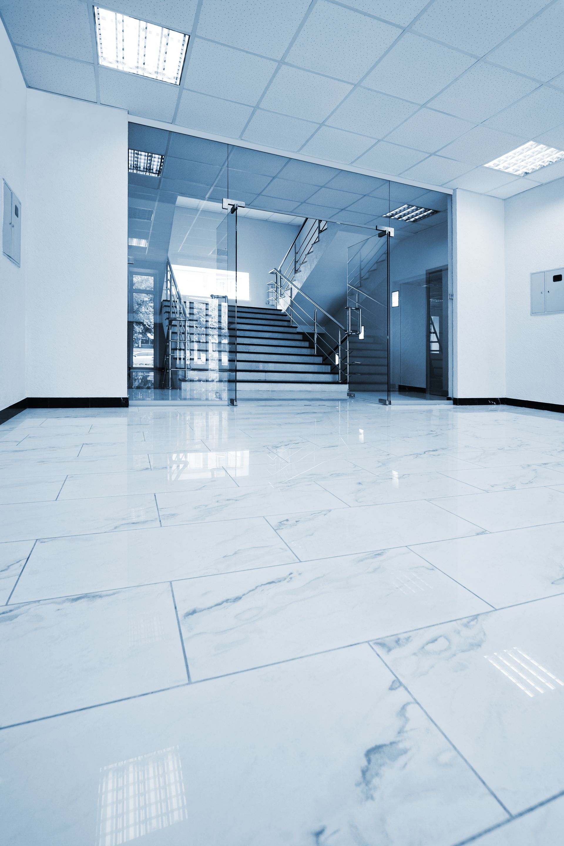 A hallway with stairs and a glass door in a building.