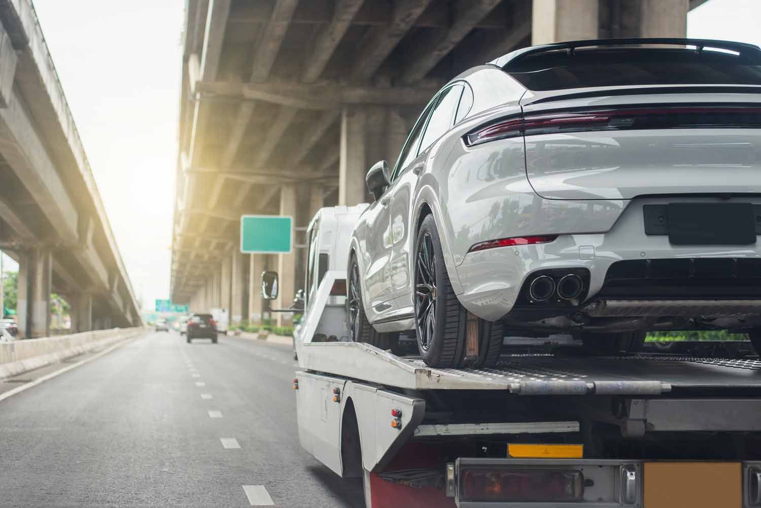 A car is being towed down a highway by a tow truck.