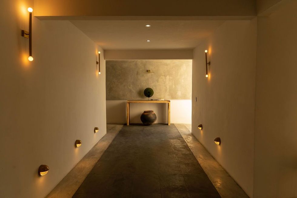 Elegante habitación con paneles de madera, sofás color crema, alfombra, lámpara de araña y ventanas arqueadas.