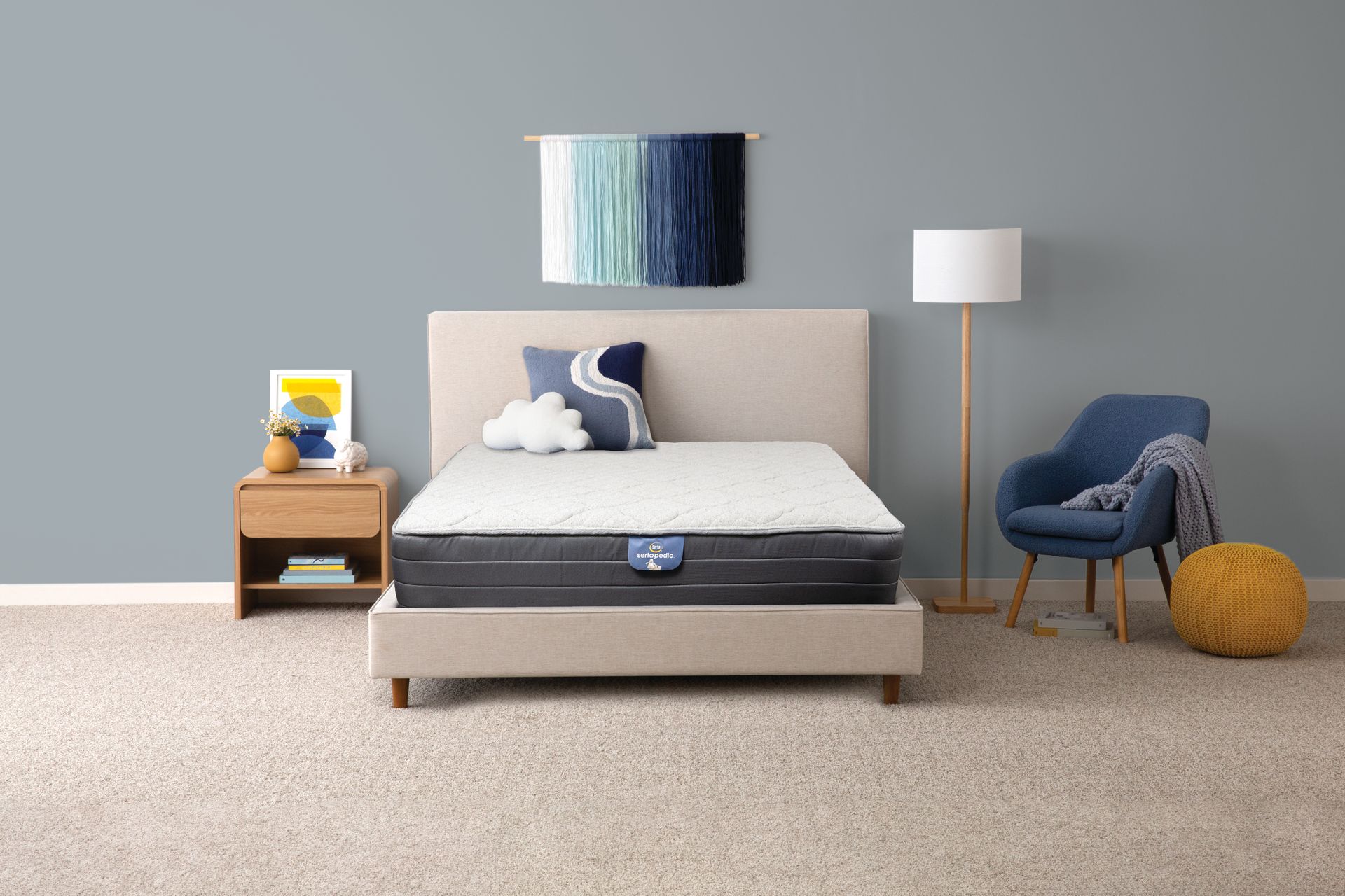 Escena de dormitorio: cama con cabecera luminosa, mesita de noche, silla, lámpara de pie, obras de arte y alfombra.