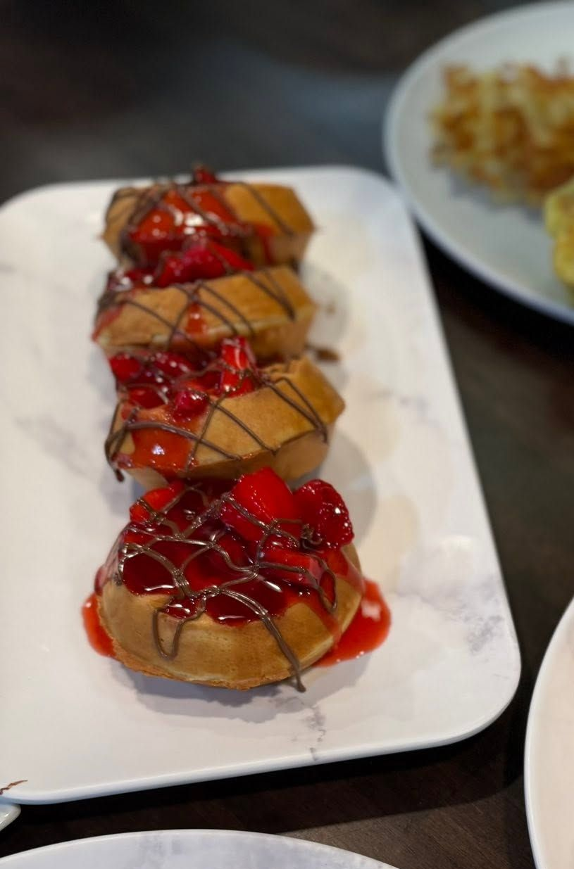 Dessert pastries topped with red sauce and chocolate drizzle on a white platter