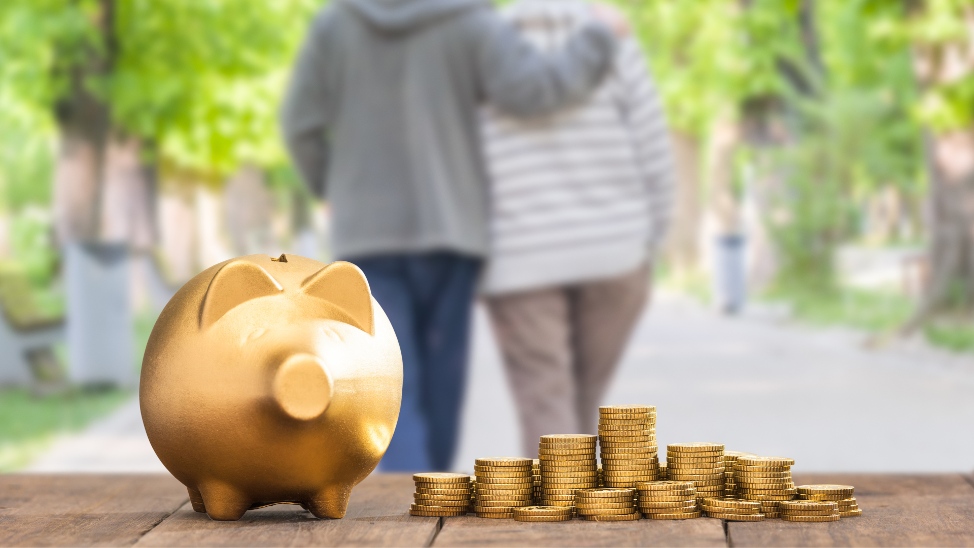 A piggy bank is sitting on a wooden table next to a pile of coins.