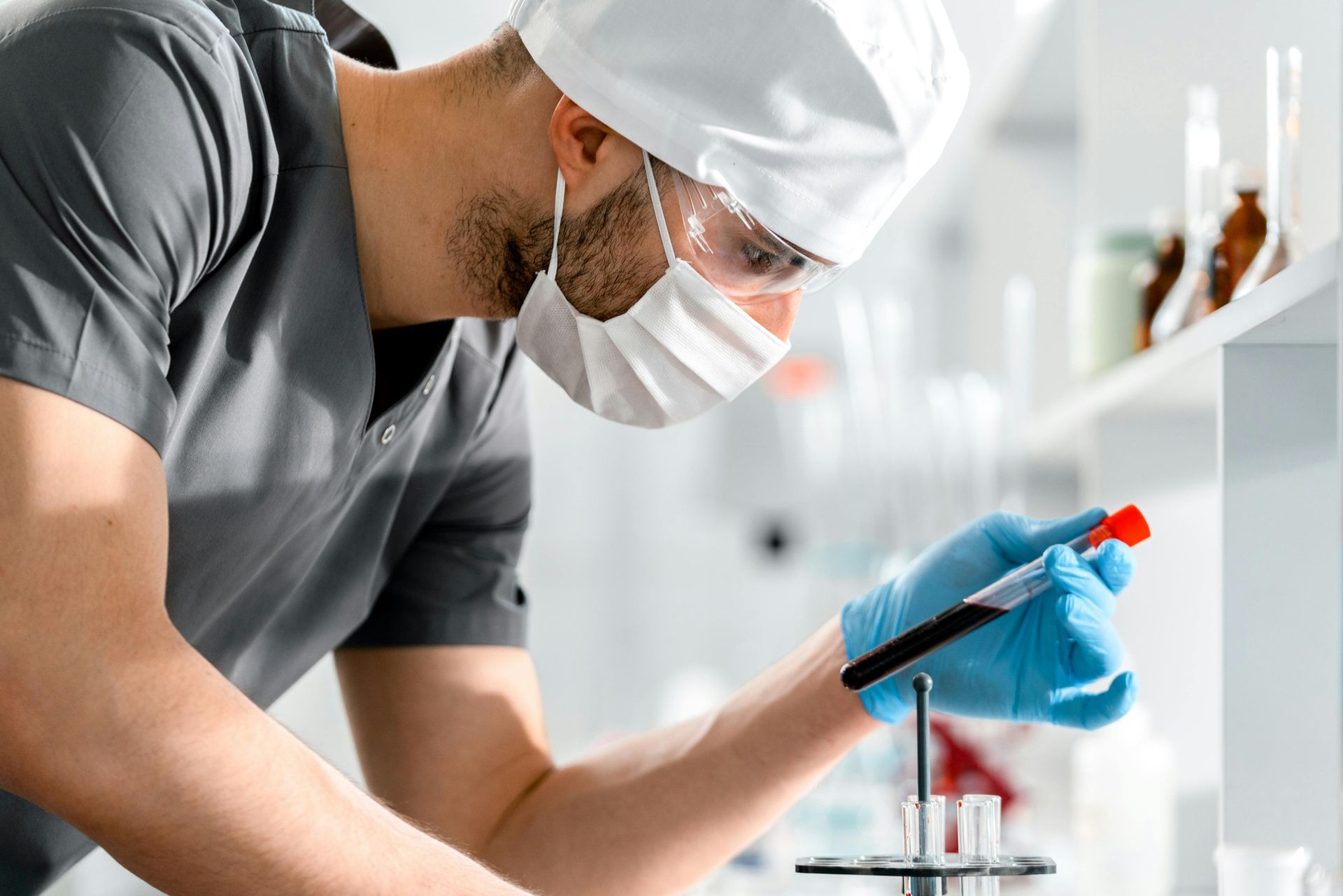 Lab technician in safety gear pipetting a liquid sample in a bright laboratory