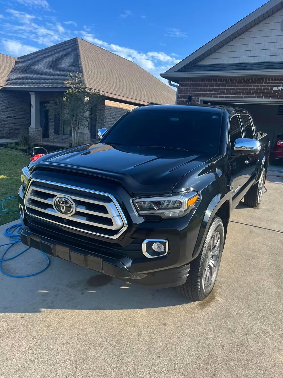 Black Toyota pickup truck parked in a driveway in front of a suburban house